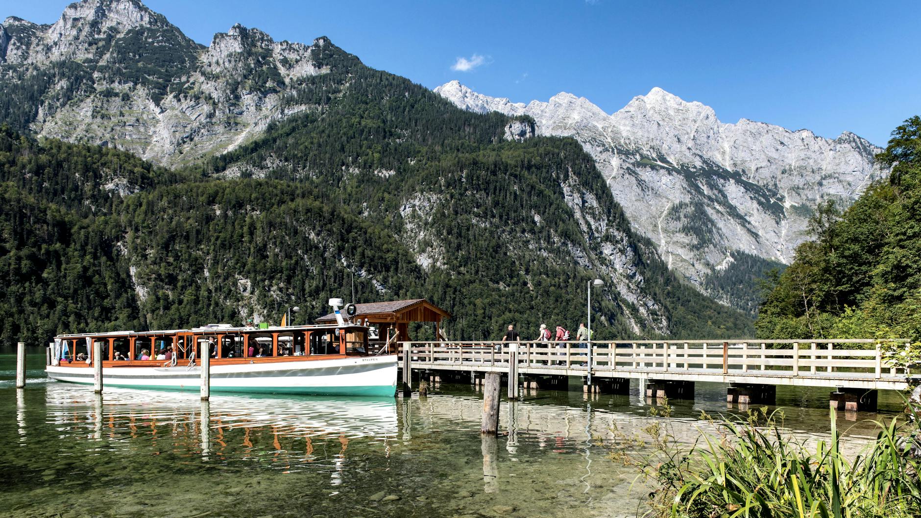 Scenic view of a tour boat and dock on Königssee with majestic Bavarian Alps in the backdrop.