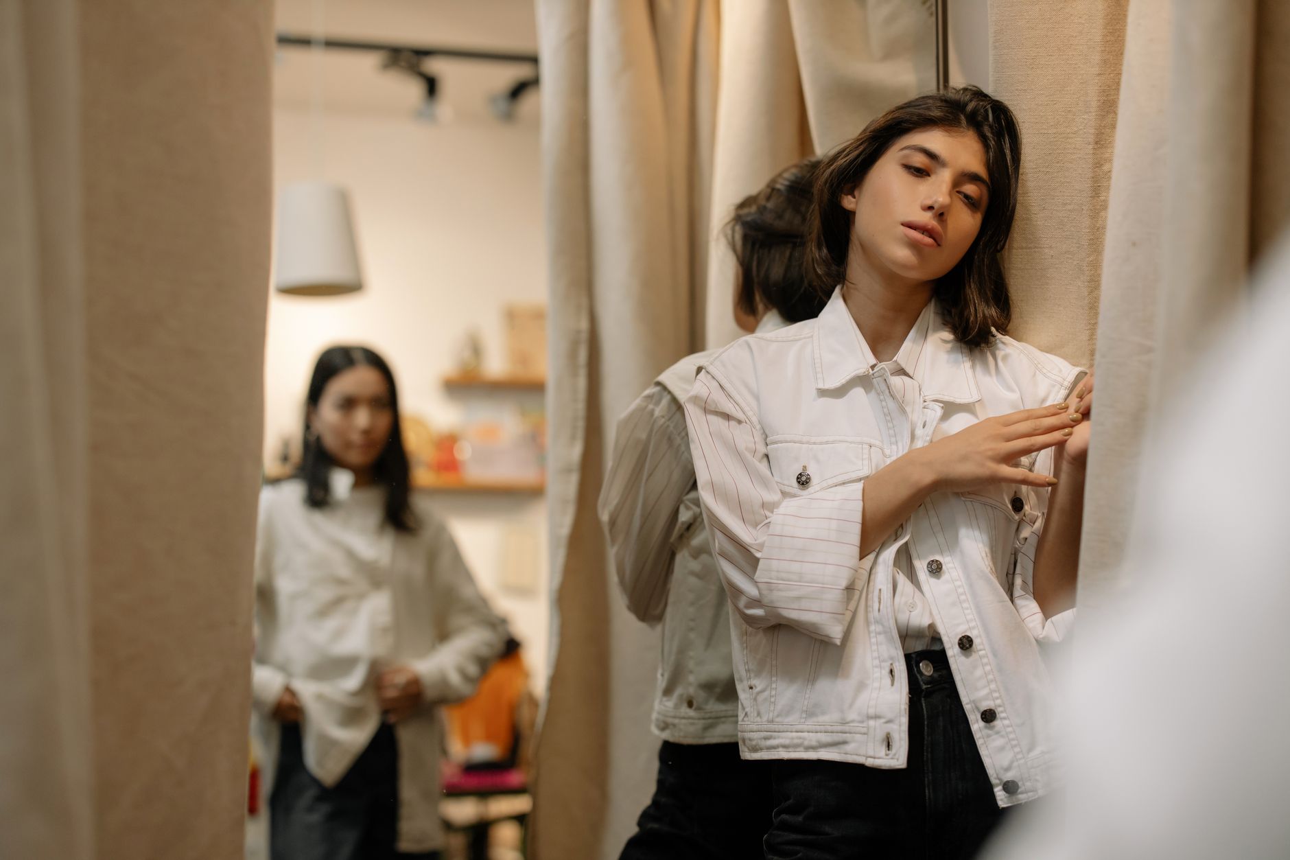 Woman in a thrift store fitting room enjoying her vintage shopping experience.